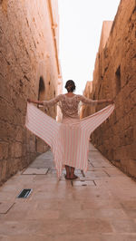 Rear view of woman sitting on wall