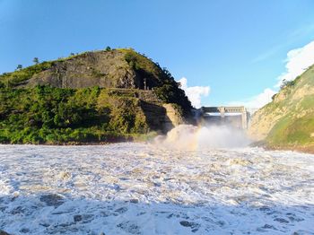 Scenic view of waterfall against clear blue sky