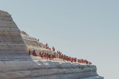 People enjoying on rock formation against clear sky