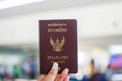 Close-up of woman hand holding passport at airport
