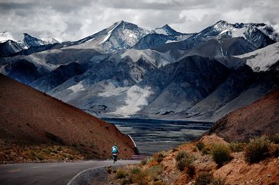 Rear view of woman cycling against snowcapped mountains 