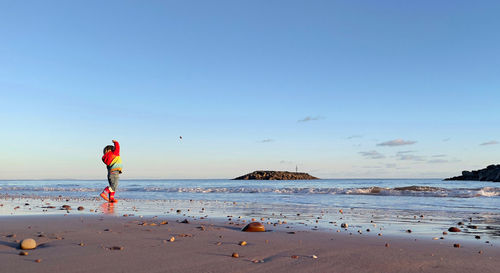 Woman standing on beach against sky