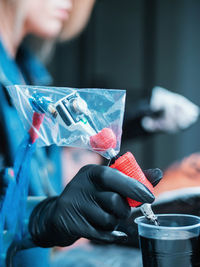 Cropped image of tattooist filling ink in tattoo machine