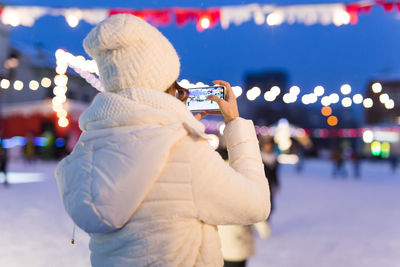 Man photographing illuminated city during winter at night