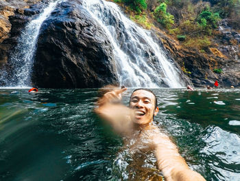 Portrait of smiling man gesturing while swimming in river