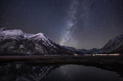 Scenic view of lake and mountains against sky at night