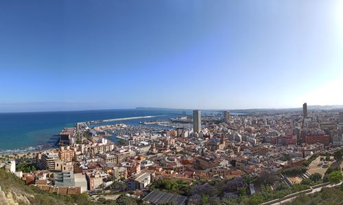 Aerial view of townscape by sea against clear sky