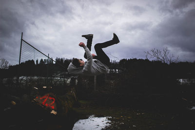 Man with arms outstretched against cloudy sky