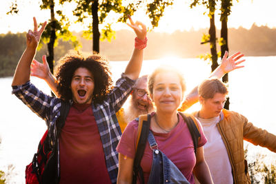 Portrait of smiling friends standing against sky