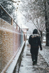 Rear view of person walking on footpath during winter