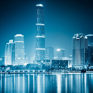 Illuminated buildings in city against clear blue sky