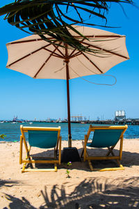 Deck chairs on beach against clear sky