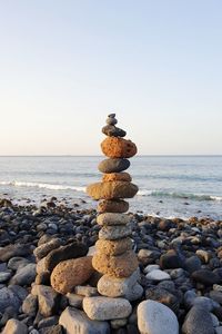 Stack of stones on beach against sky