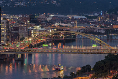 Illuminated bridge over river in city at night