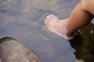 Low section of woman on rocks in lake