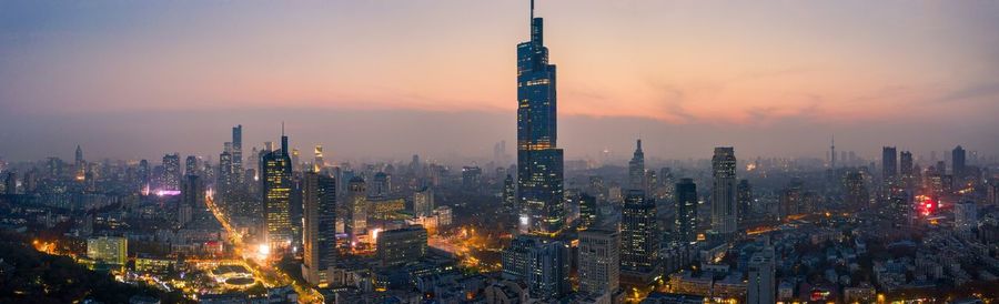 Aerial view of illuminated city buildings during sunset