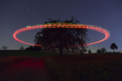 Low angle view of illuminated light painting by tree against sky at night