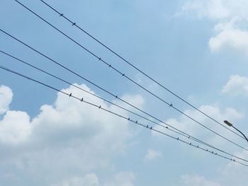 Low angle view of power cables against sky