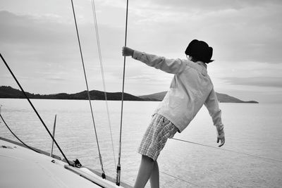 Rear view of man on sailboat against sea