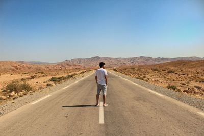 Rear view of man walking on road