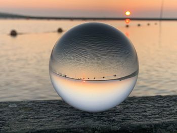 Close-up of ball on beach against sky during sunset