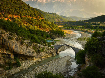 Arch bridge over river against mountains