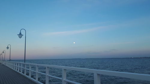 Street by sea against sky during sunset