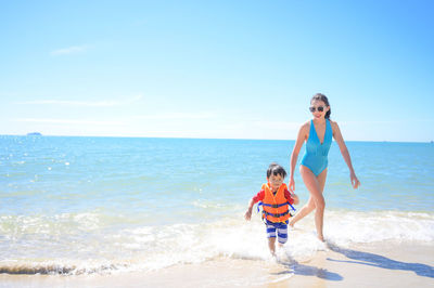 Full length of woman standing at beach against sky