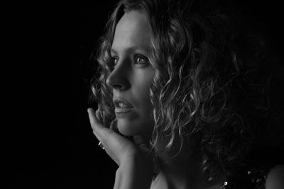 Close-up of contemplated young woman against black background