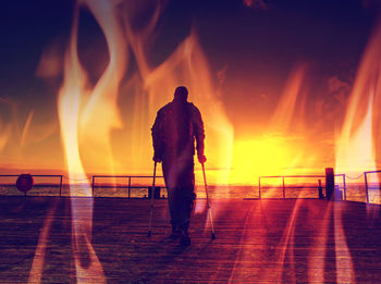 Rear view of silhouette men walking on shore against sky at night