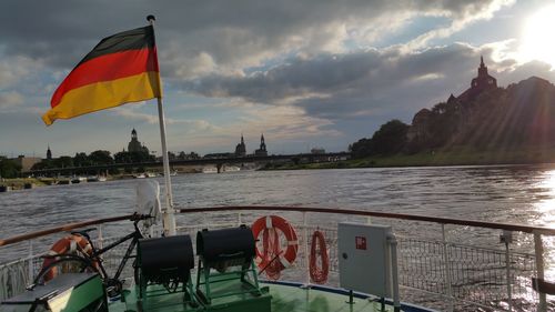 Flag by boat on river against sky