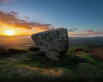 Rock on land against sky during sunset