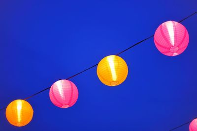 Low angle view of lanterns hanging against clear blue sky