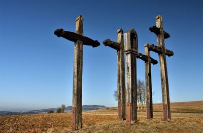 Cross on field against clear blue sky