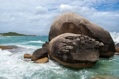 Rock formation on sea shore against sky