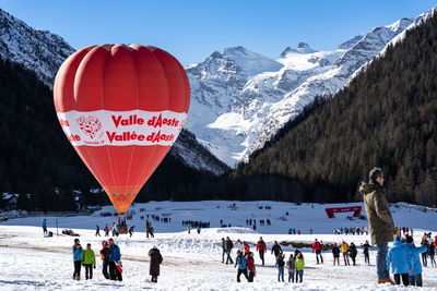 Group of people on snowcapped mountain against sky