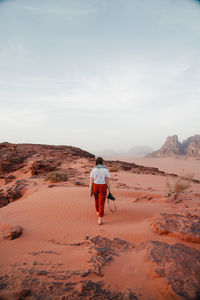 Rear view of young woman walking on field