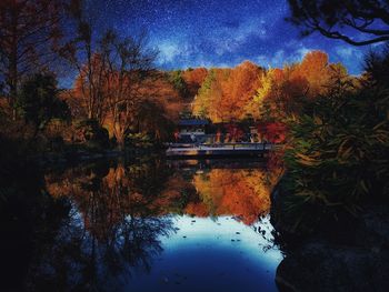 Trees by lake against sky during autumn