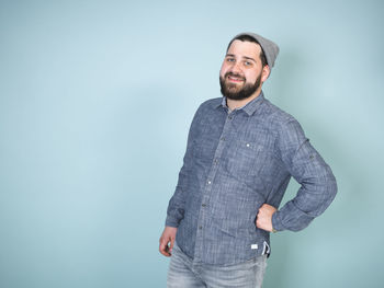 Young man standing against blue background