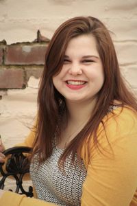 Portrait of smiling young woman sitting against wall