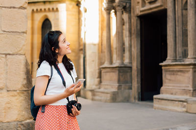 Side view of woman standing against building