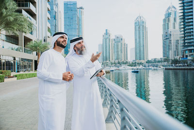 Male coworkers discussing over digital tablet while standing in city