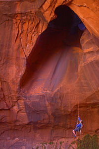 Man rappelling into cave at escalante's giant staircase