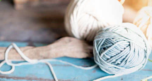 Balls of white and beige yarn on light blue wood table. threads of high-quality wool for macrame.