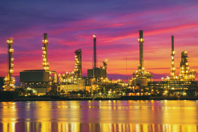 Illuminated factory against sky at night