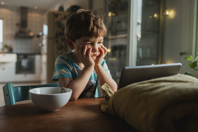 Bored boy looking at digital tablet