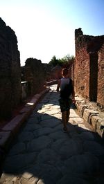 Full length rear view of man walking on cobblestone