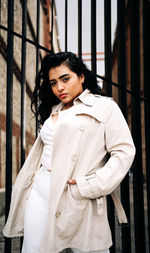 Portrait of young woman standing against wall