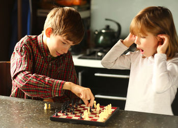 Children playing chess at home kitchen