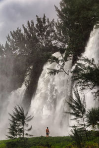 Scenic view of waterfall on field against sky